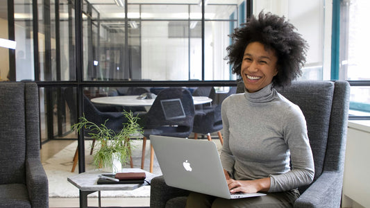 Woman smiling warmly while talking with a colleague, expressing words of affirmation in a bright modern space