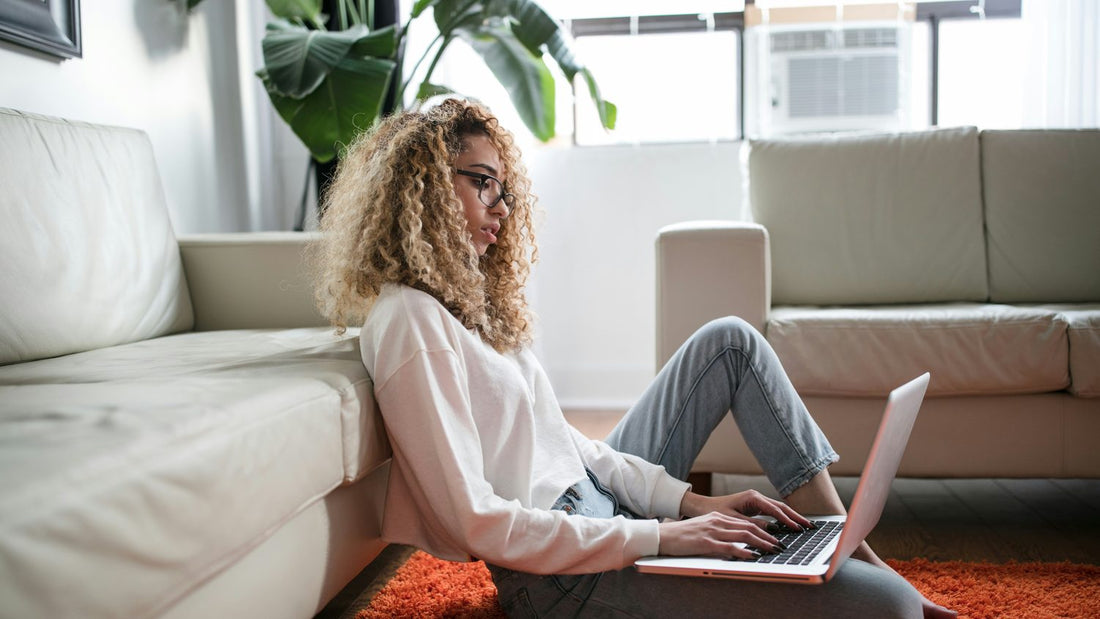 Woman sitting on the floor with a laptop, looking thoughtful while researching a dyscalculia test at home
