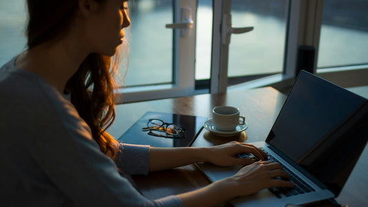 Woman at a home desk staring past her laptop, caught in a loop of repetitive ruminating thoughts
