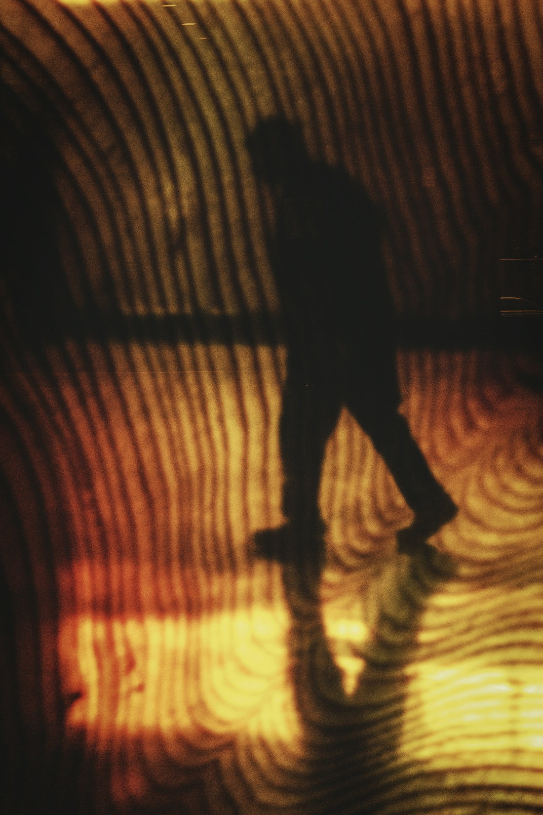 Silhouette of a person walking through a warm patterned tunnel toward light, symbolising moving past procrastination