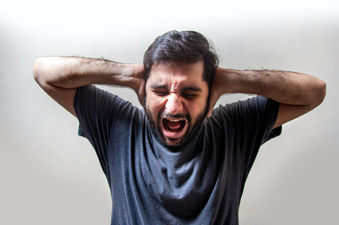 Man screaming with both hands pressed to the back of his head, depicting sensory overload and overwhelm