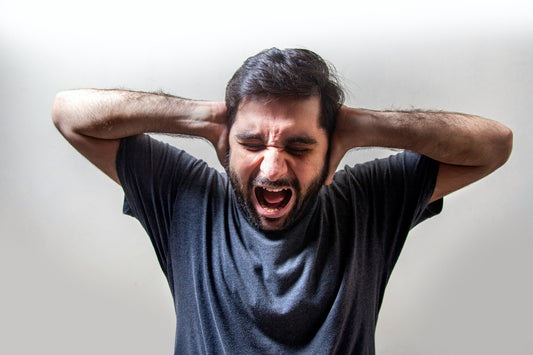 Man screaming with both hands pressed to the back of his head, depicting sensory overload and overwhelm