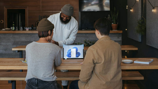 Man with headphones sitting at a laptop, hands clasped, working through a moment of tension