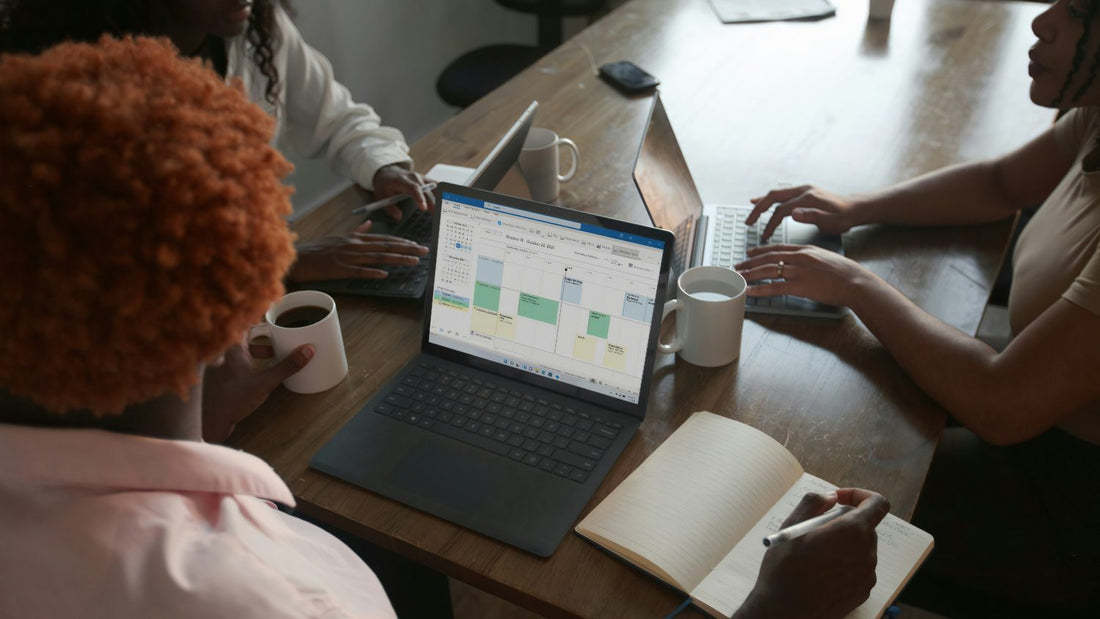 Three colleagues looking at a laptop together in a casual office, genuine gratitude in a work team