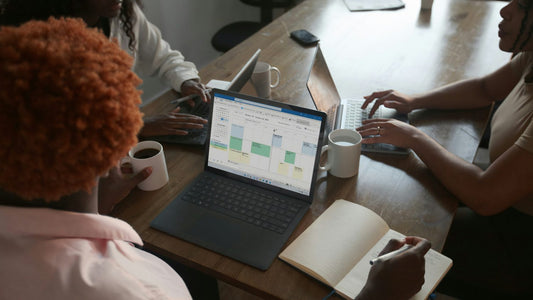 Three colleagues looking at a laptop together in a casual office, genuine gratitude in a work team