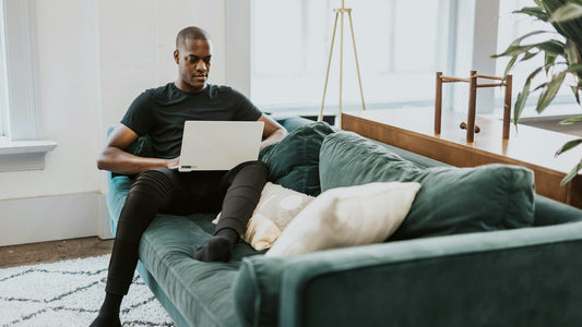 Woman sitting on the sofa with a laptop and mug, quietly working through a decision on her own terms